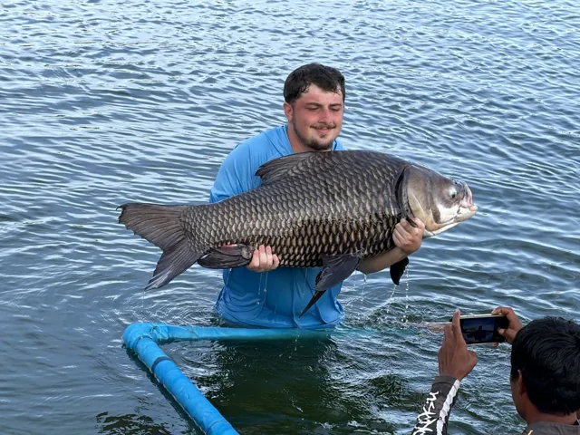 An angler supporting a fish in the lake at Hookers