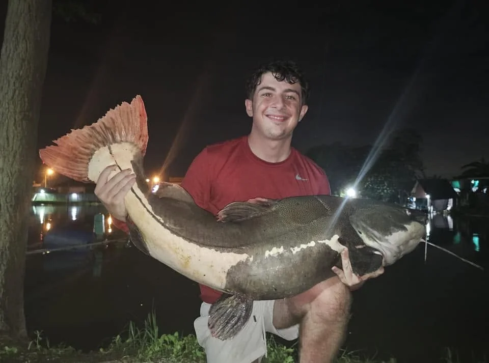 Finlay smiling with a large redtail catfish after dark.