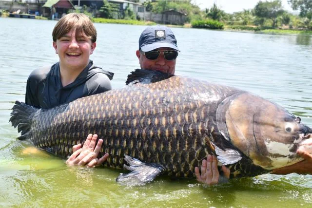Tyler and Vinny supporting a very large carp together in the lake.