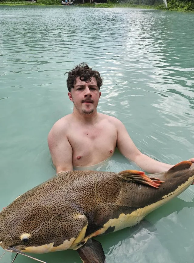 Finlay with a spotted catfish with a cream flank stripe in the lake.