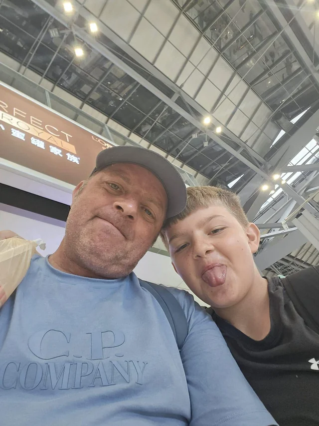 Vinny and Tyler taking a selfie beneath an airport terminal roof.